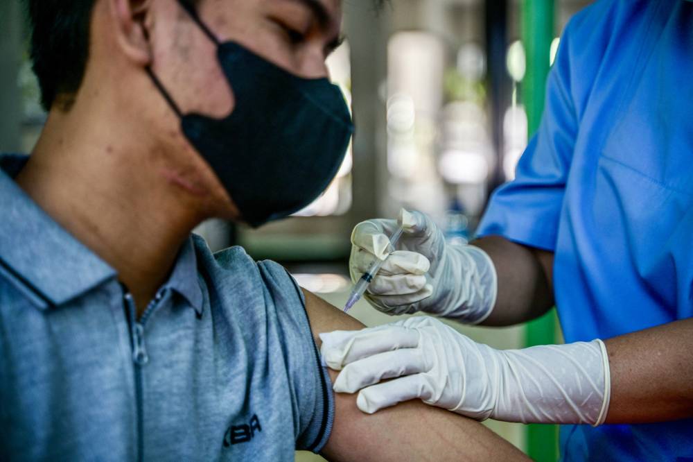 A health worker injects a man with a shot of the Inavac vaccine for Covid-19 at the Jakarta provincial health office on Dec 19, 2023. - (Photo by BAY ISMOYO / AFP)