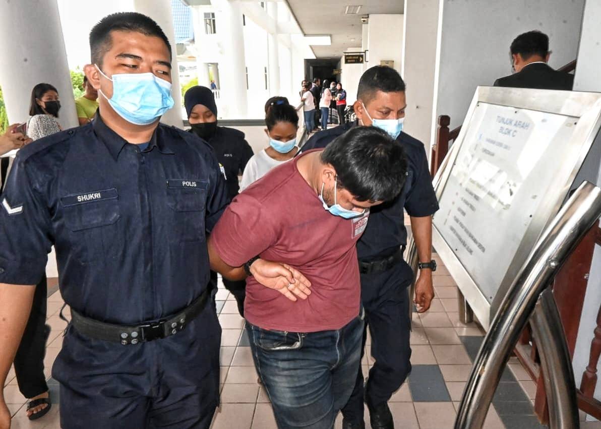 Shahezaimie (centre) while being escorted out from Ayer Keroh Sessions Court.