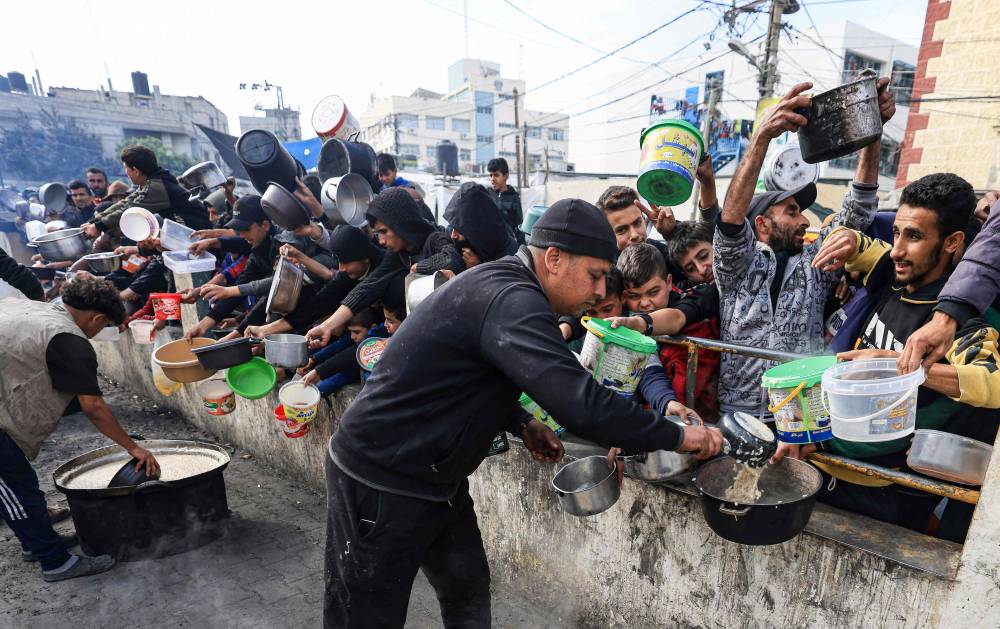 Palestinians collect food at a donation point in a refugee camp in Rafah in the southern Gaza Strip. Photo by Mahmud Hams/AFP