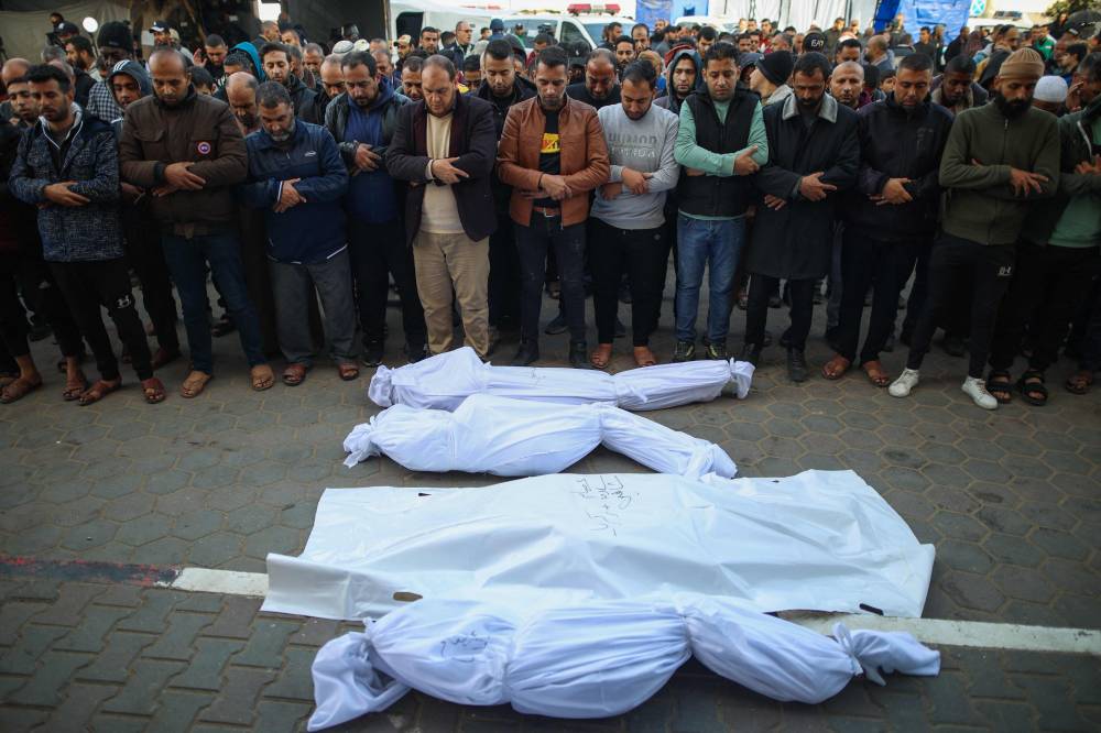 Palestinians pray by shrouded bodies of people killed following Israeli bombardment, at a hospital in Deir al-Balah in the central Gaza Strip. AFP FILE PIX