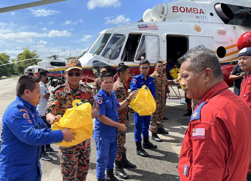 Nazili (second from left) while delivering food supply aid to the Orang Asli community at Pos Belatim here recently. Photo by Bernama