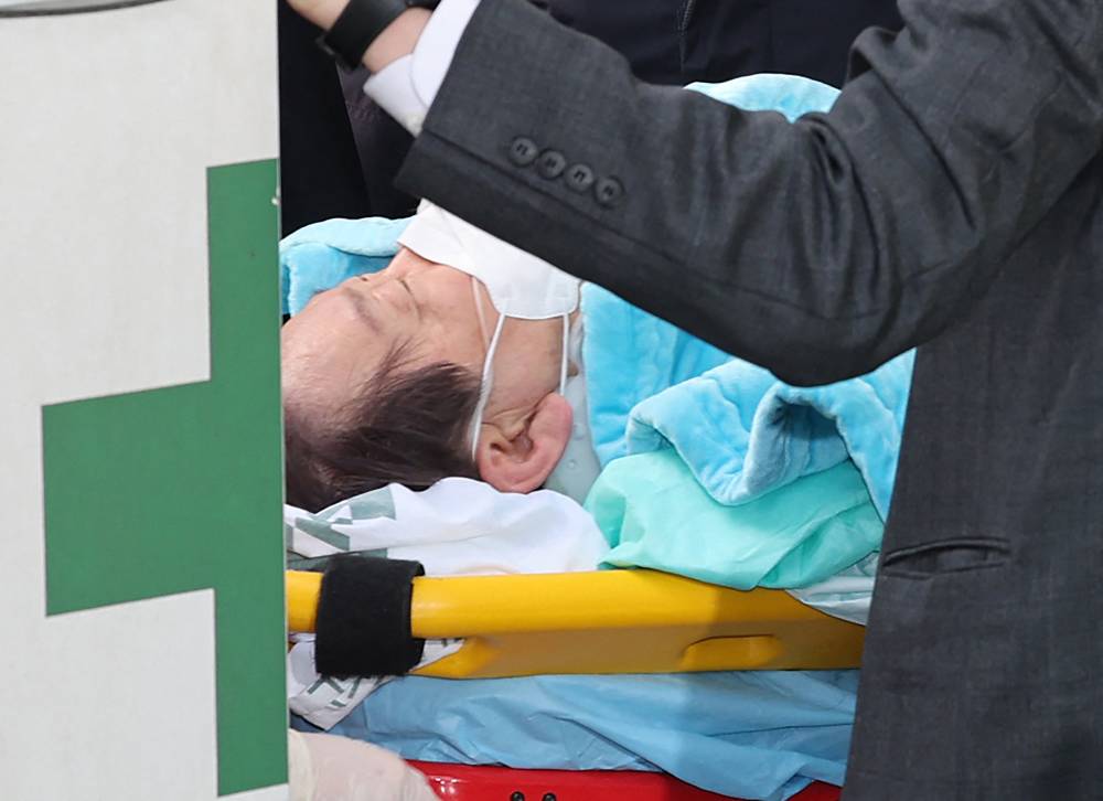 South Korean opposition party leader Lee Jae-myung, who was attacked in Busan, lies on a stretcher as he arrives at Seoul National University Hospital in Seoul on Jan 2, 2024. - (Photo by YONHAP / AFP) 