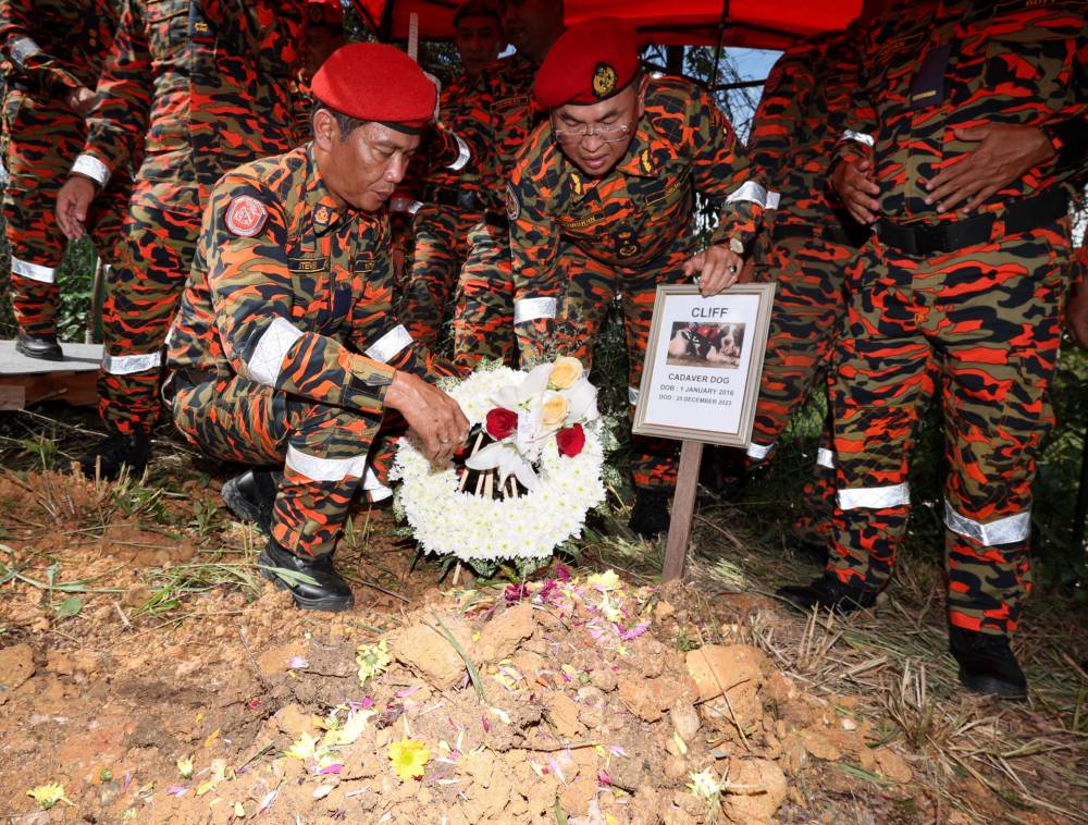 Khirudin (second, left) with K9 team paying their last respect to Cliff during its burial today. Photo by Bernama