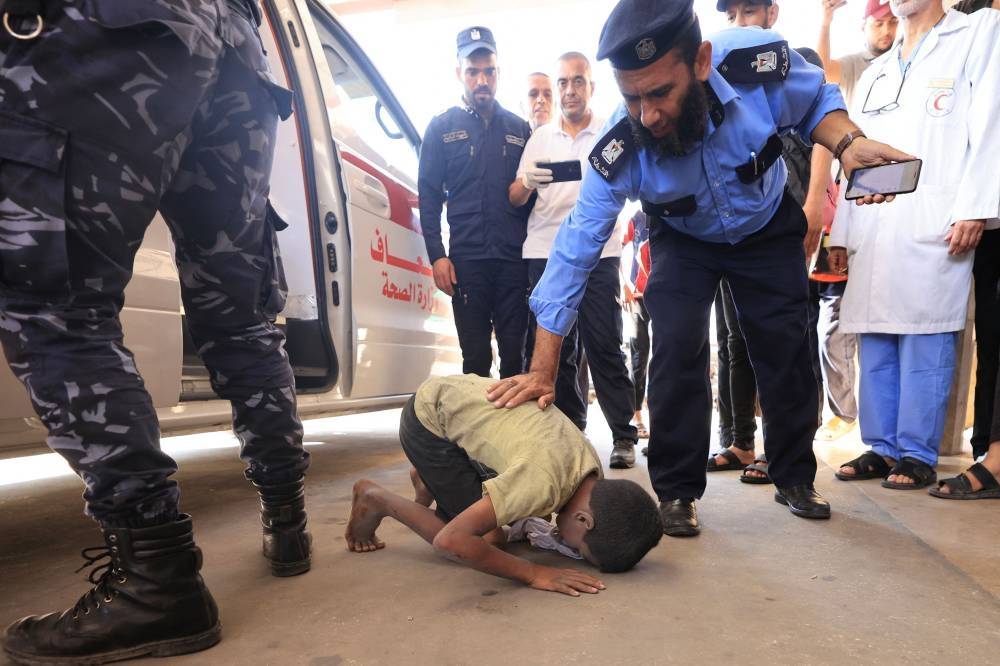 A Palestinian boy kneels to kisses the ground after being brought to a hospital following an Israeli strike, in Khan Yunis in the southern Gaza Strip on October 14, 2023. - File photo by AFP