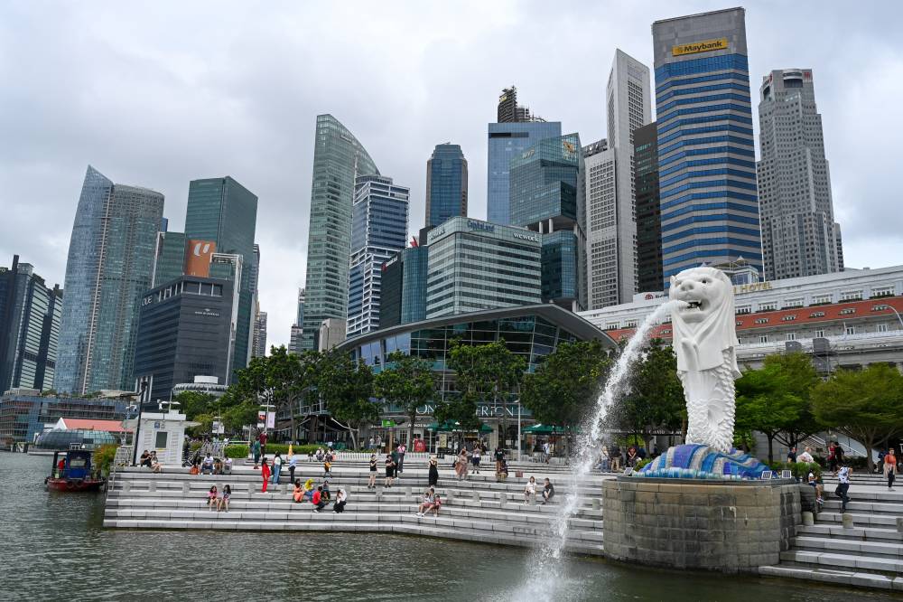 People sit on the steps near the Merlion statue near the Marina Bay waterfront in Singapore on Jan 3, 2024. (Photo by ROSLAN RAHMAN / AFP)