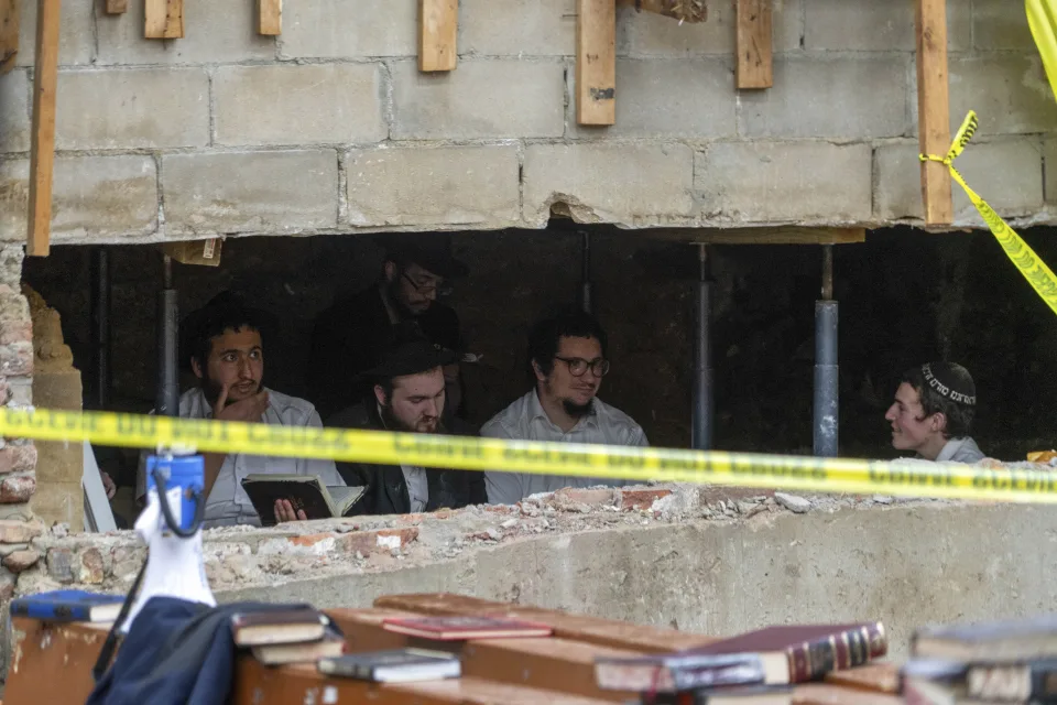 The youths sit behind a breach in the wall of a synagogue that led to a tunnel dug by the students, Monday, Jan 8, 2024, in New York. (Photo by Bruce Schaff via AP)