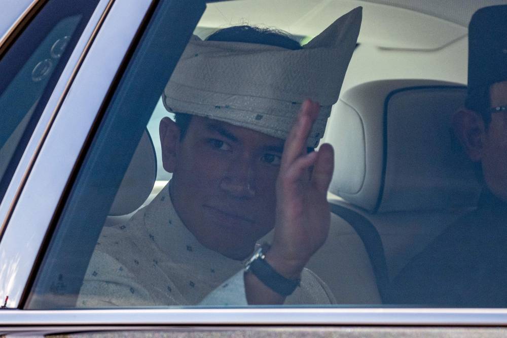 Brunei's Prince Abdul Mateen waves from his car as he leaves following his solemnization as part of the royal wedding at Sultan Omar Ali Saifuddien Mosque in Bandar Seri Begawan in Brunei on Jan 11, 2024. (Photo by Mohd RASFAN / AFP)