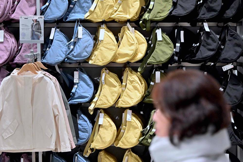 A woman walks past a display of bags at a Uniqlo retail store in Tokyo on Jan 16, 2024. Japanese fashion giant Uniqlo said on Jan 16 that it is suing Chinese rival Shein over copycats of a massively popular crossbody pouch dubbed online the "Mary Poppins carryall". - (Photo by RICHARD A. BROOKS / AFP)