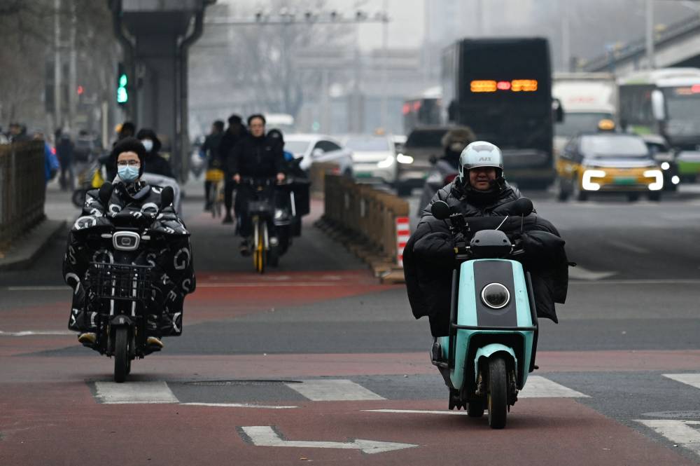 People ride motocycles along a road in Beijing on January 17, 2024. - Photo by AFP