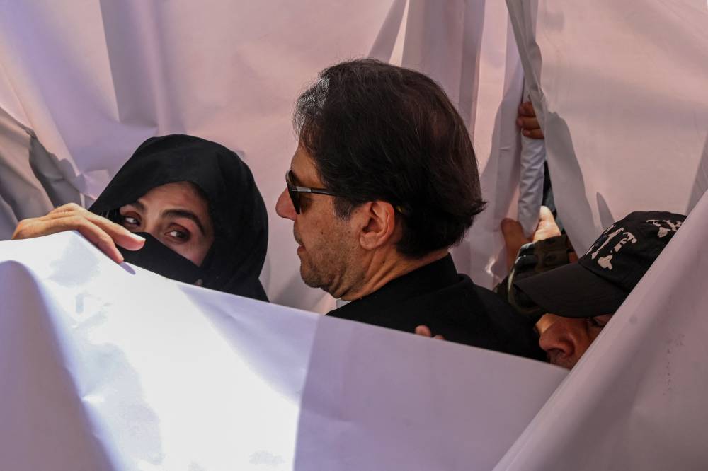 Former Pakistan Prime Minister Imran Khan (C) with his wife Bushra Bibi (L) arrive to appear at a high court in Lahore on May 15, 2023.Khan and his wife were sentenced on Jan 31, 2024, to 14 years in jail after being found guilty of graft in a case involving gifts he received while premier. (Photo by ARIF ALI / AFP)