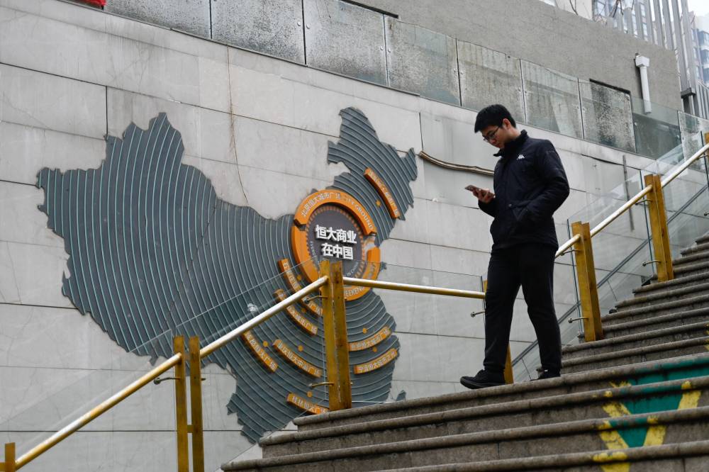A man walks past a map of China which shows Evergrande commercial complexes at a partially operating Evergrande commercial complex in Beijing on January 30, 2024. - Photo by AFP