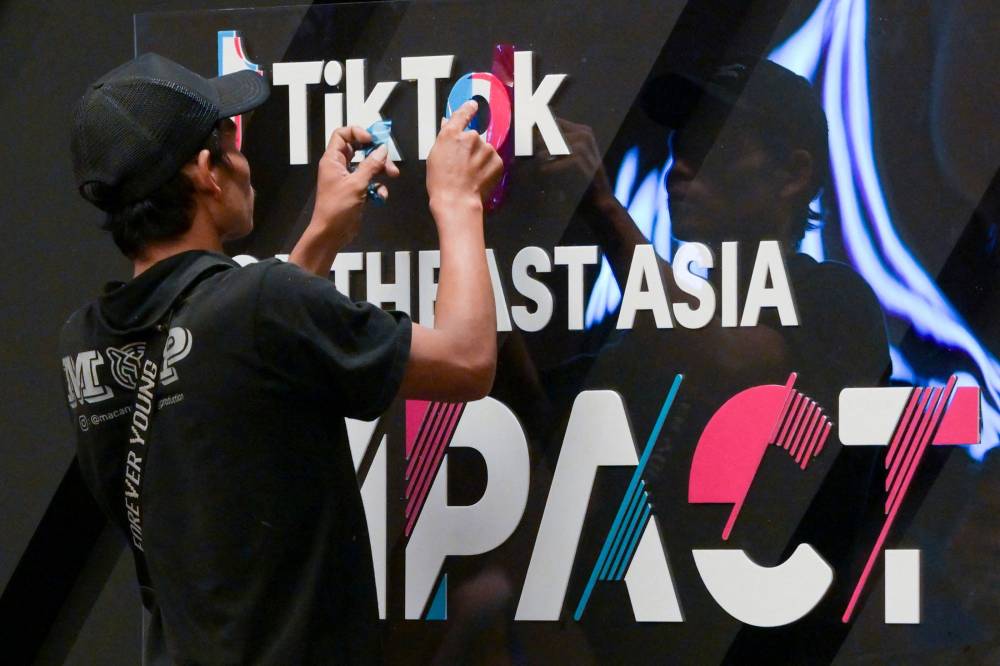 This picture taken on June 15, 2023 shows a worker finishing signage before the TikTok Southeast Asia Impact Forum 2023 in Jakarta. Small armies of grassroot factcheckers are battling a wave of election-related misinformation in the world's third-largest democracy, dedicating spare time to debunk posts before the February 14 presidential vote. Nations worldwide are expressing worry about election misinformation, but Indonesia's enormous social media audience makes its presidential vote particularly vulnerable. = Photo by AFP