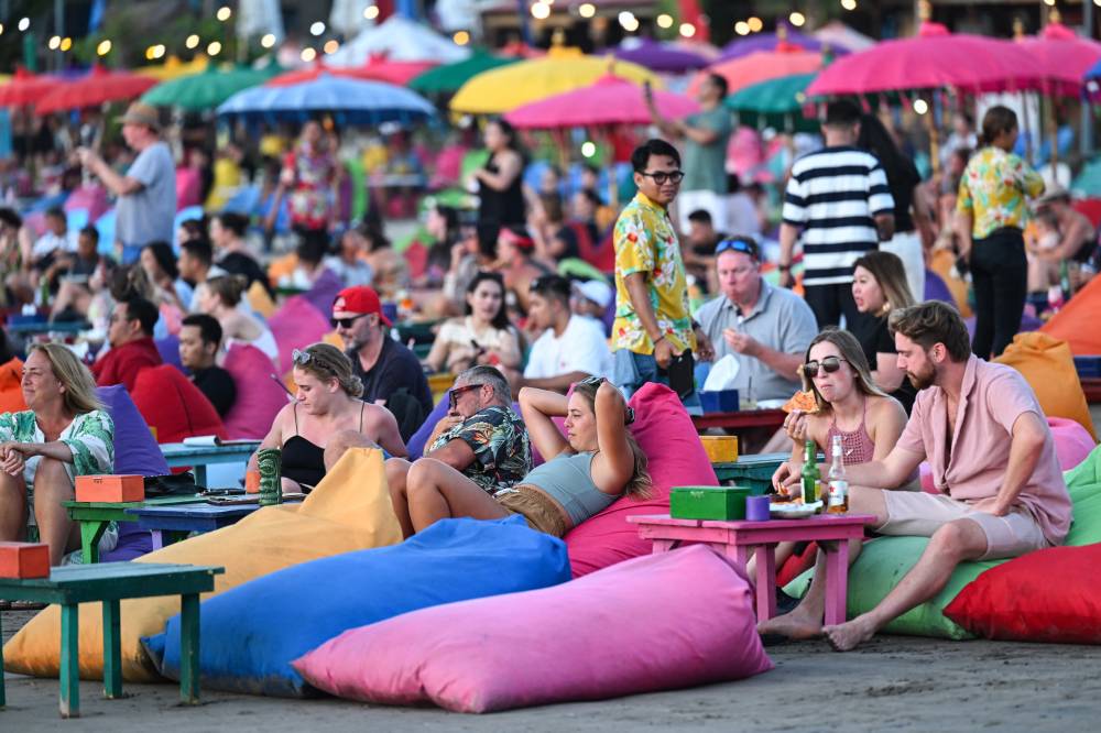 Foreign tourists relax on the Kuta Beach near Denpasar on Indonesia's resort island of Bali on Nov 18, 2023. - (Photo by SONNY TUMBELAKA / AFP)