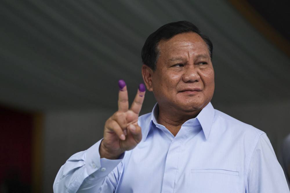 Indonesia's presidential candidate Prabowo Subianto gestures after staining his fingers with ink at a polling station after he voted in Indonesia’s presidential and legislative elections in Bogor, West Java on Feb 14, 2024. - (Photo by YASUYOSHI CHIBA / AFP)
