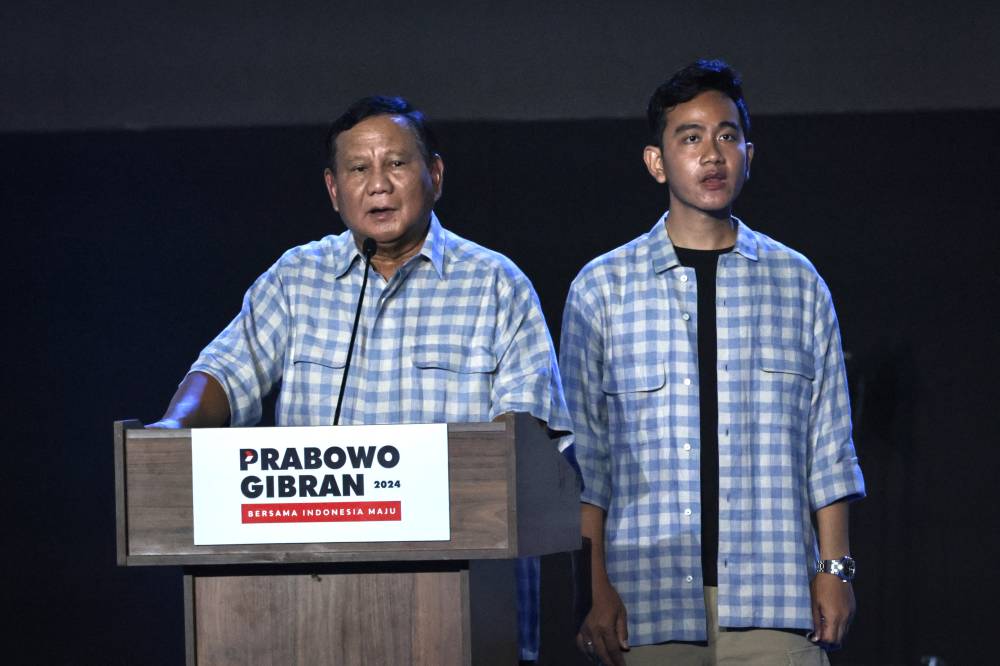 Presidential candidate and Indonesia’s Defence Minister Prabowo Subianto (L) speaks on the stage with vice presidential candidate Gibran Rakabuming Raka, Indonesian President Joko Widodo's son and current Surakarta City mayor, during their gathering with supporters after polls closed in the country’s presidential and legislative elections in Jakarta on Feb 14, 2024. - (Photo by YASUYOSHI CHIBA / AFP)