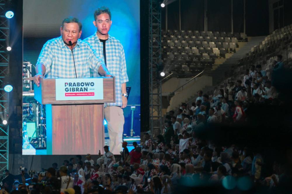 A large screen projects Indonesian presidential candidate Prabowo Subianto (L) as he addresses supporters next to vice presidential candidate Gibran Rakabuming Raka (R), the son of Indonesian President Joko Widodo and current Surakarta City mayor, after polls closed in the country’s presidential and legislative elections in Jakarta on February 14, 2024. - Photo by AFP