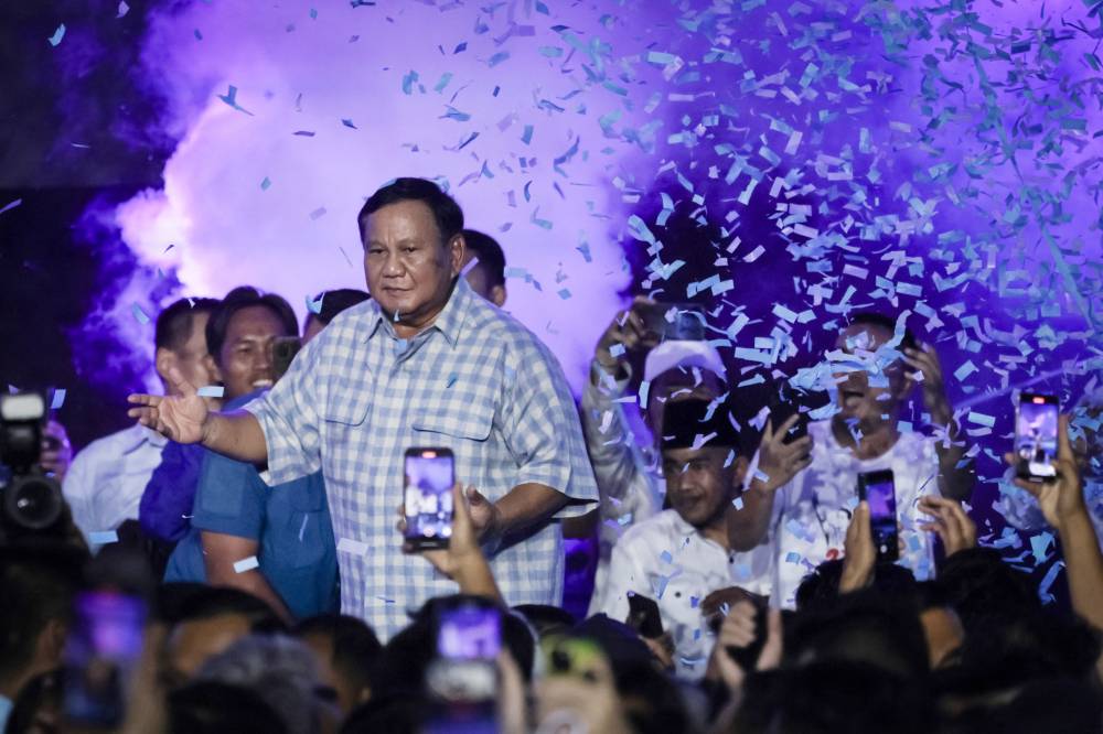 Presidential candidate and Indonesia's Defence Minister Prabowo Subianto (C) dances on the stage during a gathering with supporters after polls closed in the country’s presidential and legislative elections in Jakarta on Feb 14, 2024. - (Photo by YASUYOSHI CHIBA / AFP)