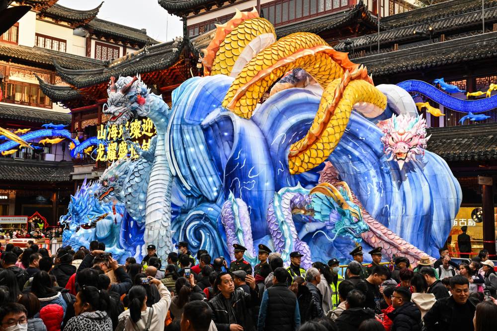 People take pictures of an illuminated installation of a dragon at the Yu Garden during the fourth day of the Lunar New Year of the Dragon in Shanghai on February 13, 2024. (Photo by HECTOR RETAMAL / AFP)