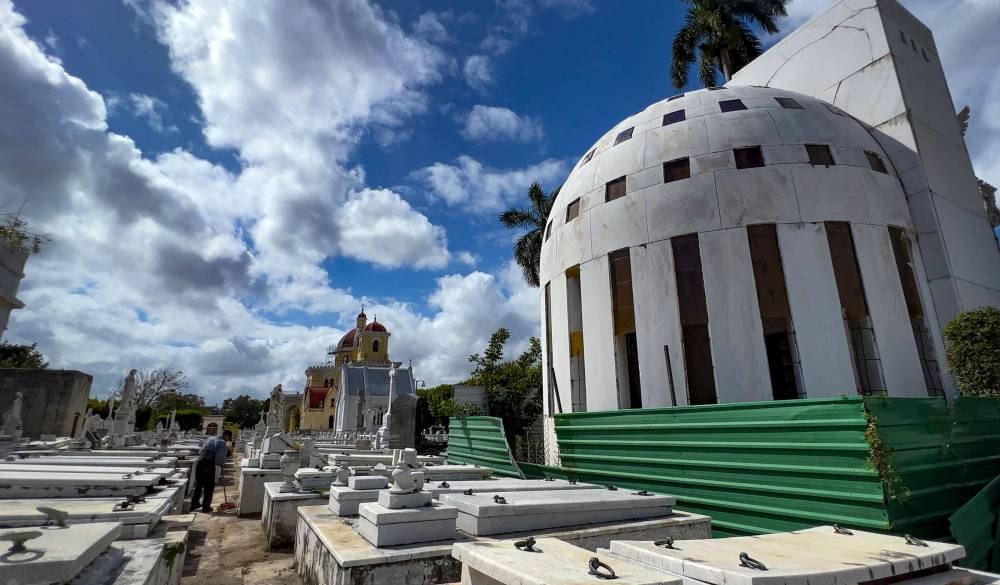 An employee of the Colon Cemetery cleans among the graves near the mausoleum of Catalina Lasa and Juan Pedro Baro (R) in Havana. Photo by Adalberto Roque/AFP