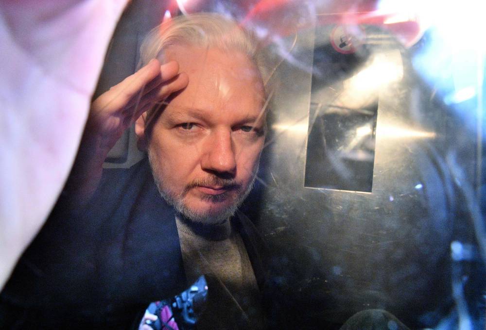 (FILES) WikiLeaks founder Julian Assange gestures from the window of a prison van as he is driven out of Southwark Crown Court in London on May 1, 2019, after having been sentenced to 50 weeks in prison for breaching his bail conditions in 2012. (Photo by Daniel LEAL / AFP)