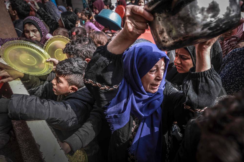 Displaced Palestinians gather to receive food at a government school in Rafah in the southern Gaza Strip on February 19, 2024. (Photo by MOHAMMED ABED / AFP)