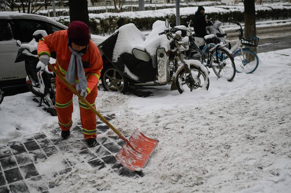 A worker clears snow off a street in Beijing on February 21, 2024. - Photo by AFP