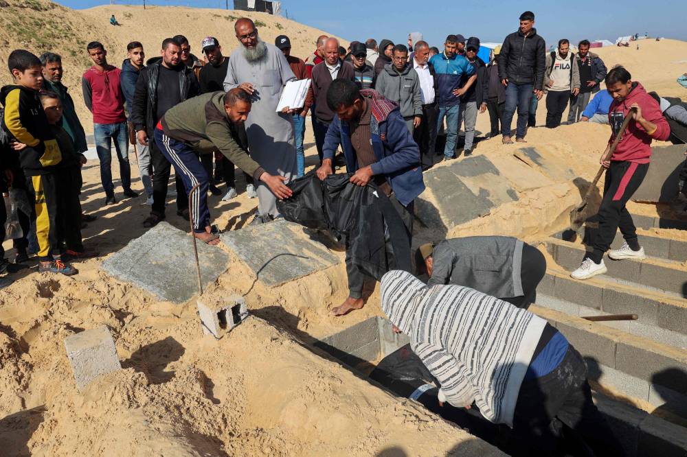 Palestinians bury their dead following overnight Israeli strikes at a cemetery in Rafah, on the southern Gaza Strip on February 21, 2024. - Photo by AFP