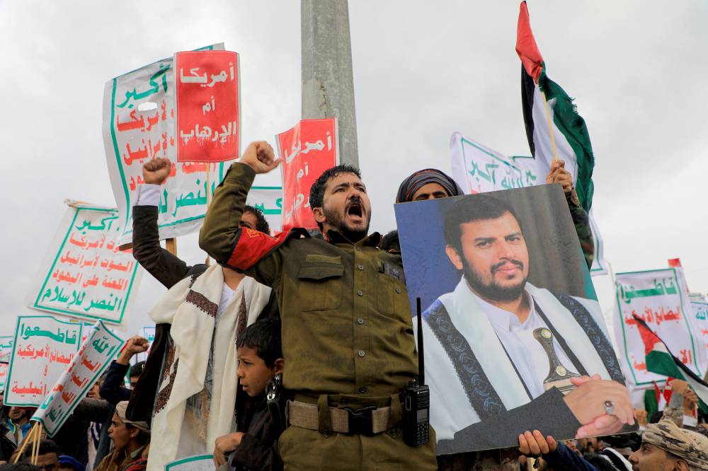 A protester lifts a portrait of Huthi leader Abdul-Malik al-Huthi during a rally in the Huthi-controlled capital Sanaa on Jan 19, 2024, protesting the US designation of Yemen's Huthi rebels as "terrorists", after a series of attacks on Red Sea shipping amid Israeli attacks on Gaza. - (Photo by MOHAMMED HUWAIS / AFP)