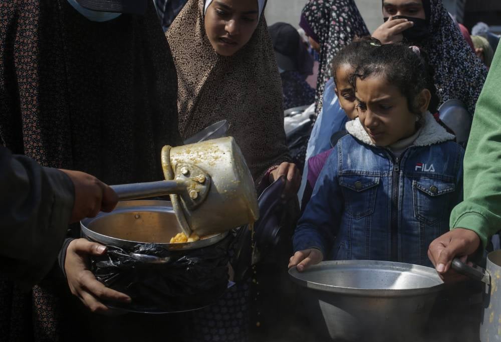 Internally displaced Palestinians receive food provided by Arab and Palestinian donors in Deir Al Balah town, southern Gaza Strip, 24 February 2024. (Photo by EPA/MOHAMMED SABER)