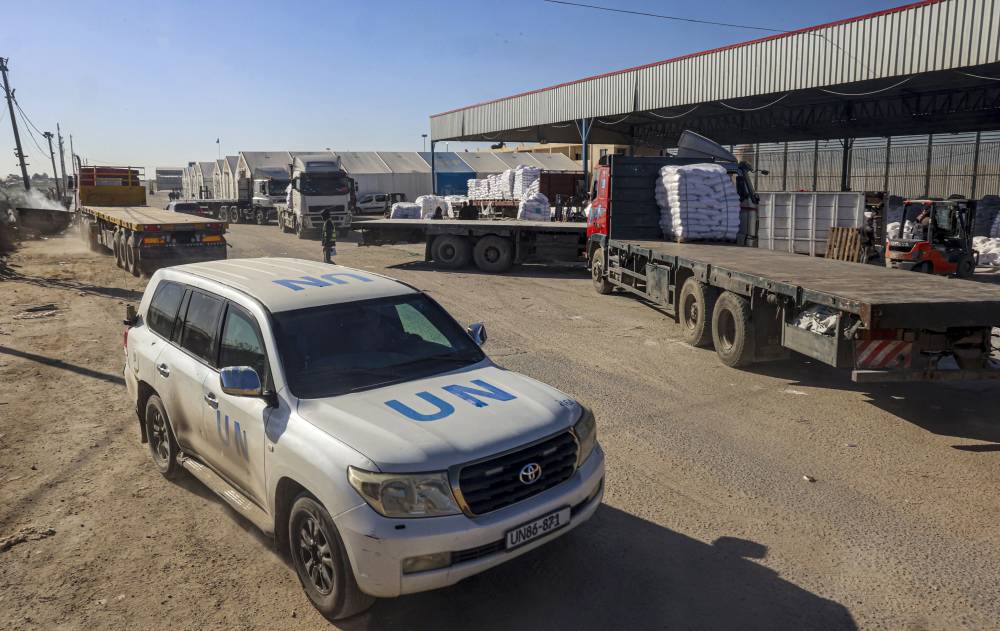 A United Nations car drives past trucks delivering humanitarian aid that entered Gaza by truck through Karm Abu Salem border crossing in the southern part of the Palestinian territory on Feb 17, 2024, in Rafah on the southern Gaza Strip. - (Photo by SAID KHATIB / AFP)