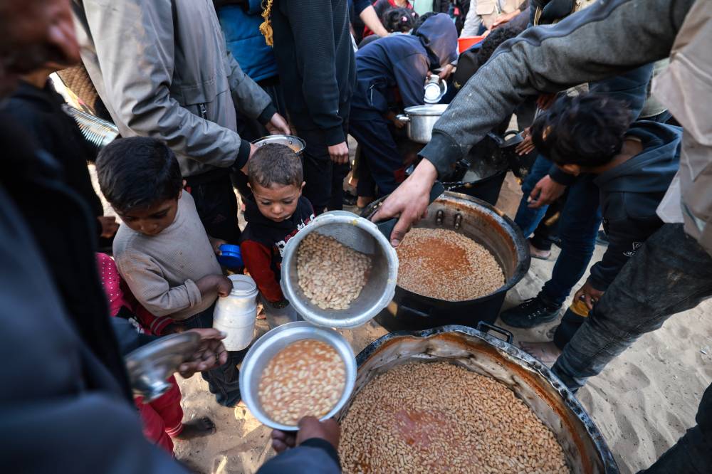 Displaced Palestinians collect food donated by a charity before an iftar meal, the breaking of fast, on the first day of the Muslim holy fasting month of Ramadan, in Rafah in the southern Gaza Strip on March 11, 2024. - (Photo by MOHAMMED ABED / AFP)