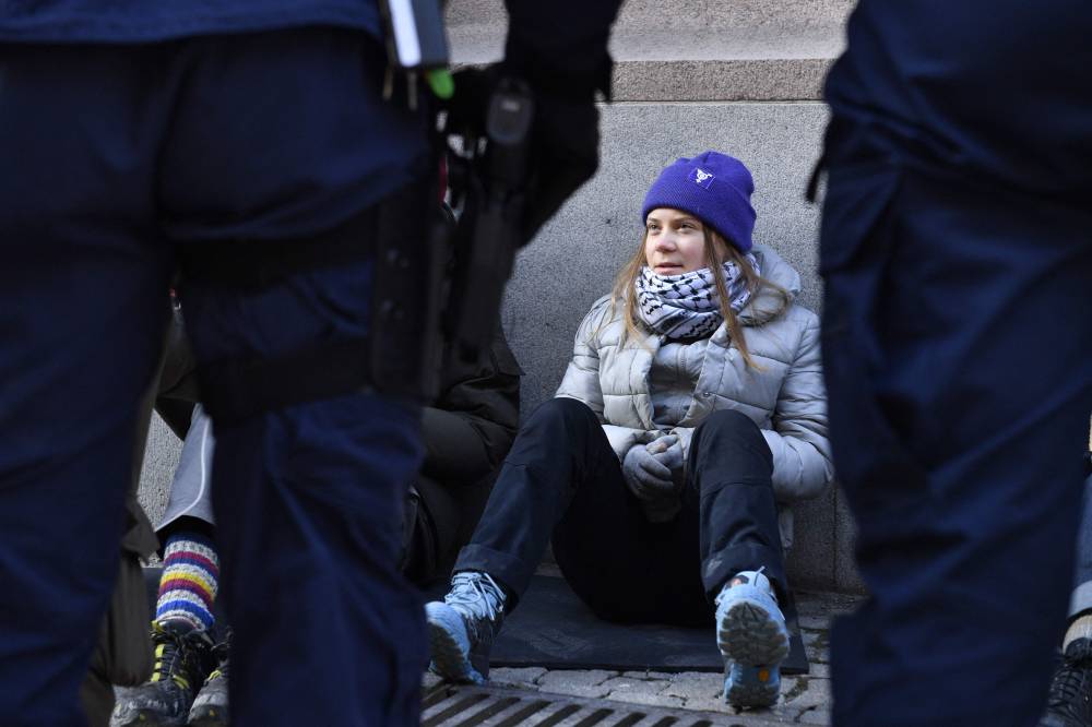 Swedish climate activist Greta Thunberg looks at policemen as she sits outside the Swedish parliament, the Riksdagen, to demonstrate for climate action. Photo by Samuel Steen/AFP