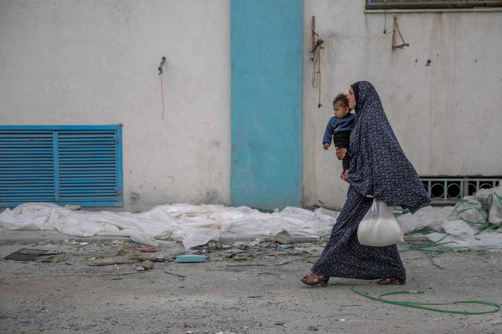 A woman carries her child and a bag of flour after humanitarian aid was distributed in Gaza City on March 17. Photo for illustrative purposes only - AFP