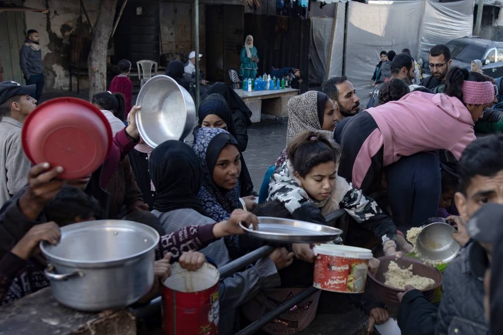 epa11239268 Internally displaced Palestinians gather to collect food donated by a charitable group before breaking the fast during the Muslim holy month of Ramadan in Rafah, southern Gaza Strip, 23 March 2024. Since 07 October 2023, up to 1.9 million people, or more than 85 percent of the population, have been displaced throughout the Gaza Strip, some more than once, according to the United Nations Relief and Works Agency for Palestine Refugees in the Near East (UNRWA), which added that most civilians in Gaza are in 'desperate need of humanitarian assistance and protection'. EPA/HAITHAM IMAD