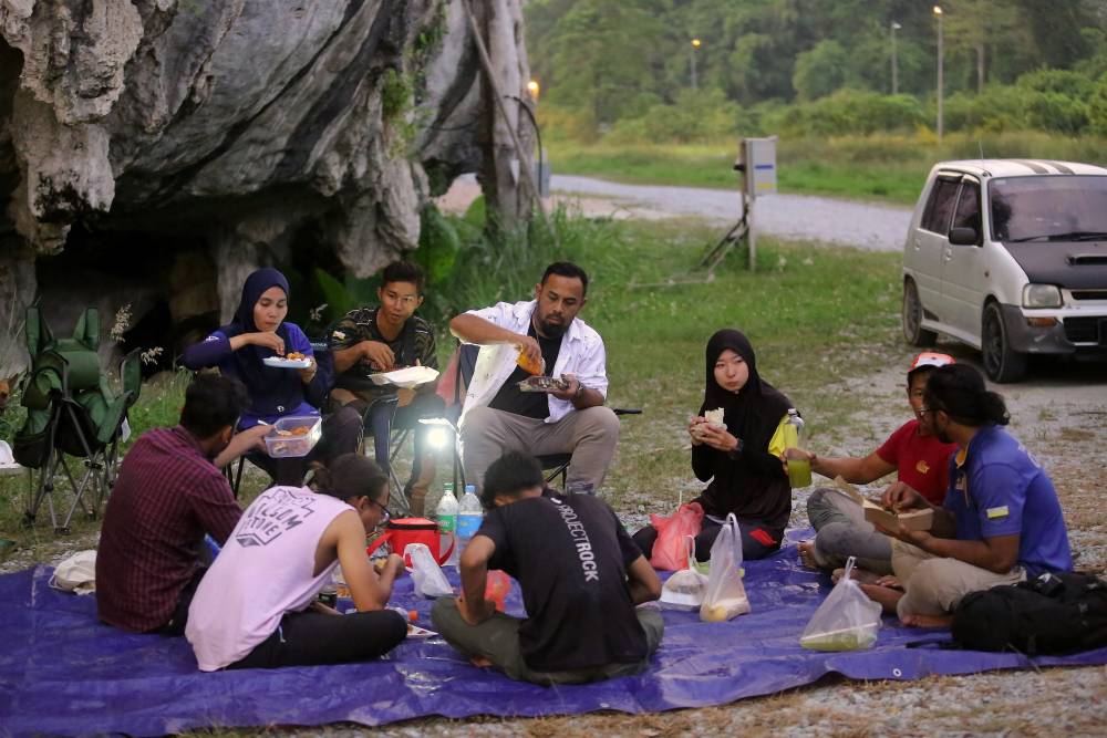 Kanako Wakabayashi, 28, (third, right) said a prayer before breaking the fast with her friends at Gua Mat Soorat. Photo by Bernama