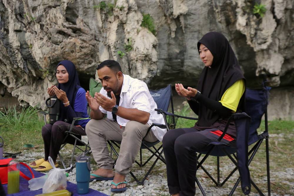 Kanako Wakabayashi, 28, (right) said a prayer before breaking the fast with her friends at Gua Mat Soorat. Photo by Bernama