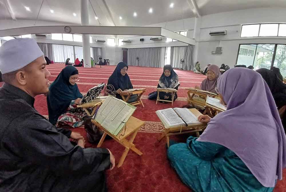 Mohd Hanifah (left) listens to the recitation from his student during a Quranic study session at the Tengku Ampuan Afzan Mosque, Indera Mahkota, Kuantan.