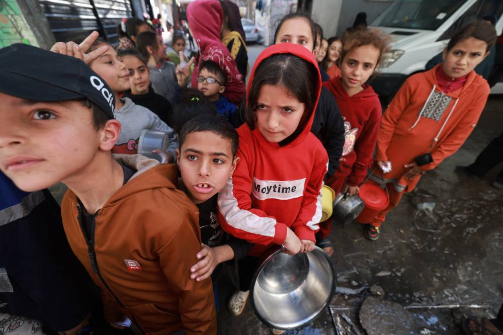 Palestinian children receive cooked food rations as part of a volunteer youth initiative in Rafah in the southern Gaza Strip, on March 5, 2024, amid widespread hunger in the besieged Palestinian territory. - (Photo by MOHAMMED ABED / AFP)