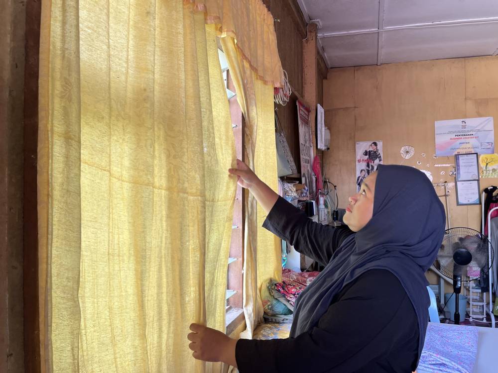 Siti Norsyakila Kamarzaman, 35, installs new curtains for upcoming Aidilfitri. Photo by Bernama