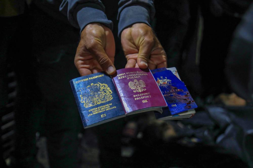 A man displays British, Polish, and Australian passports next to the bodies of World Central Kitchen workers at Al-Aqsa Hospital in Deir al-Balah, Gaza Strip, on April 1, 2024. - Photo by AFP