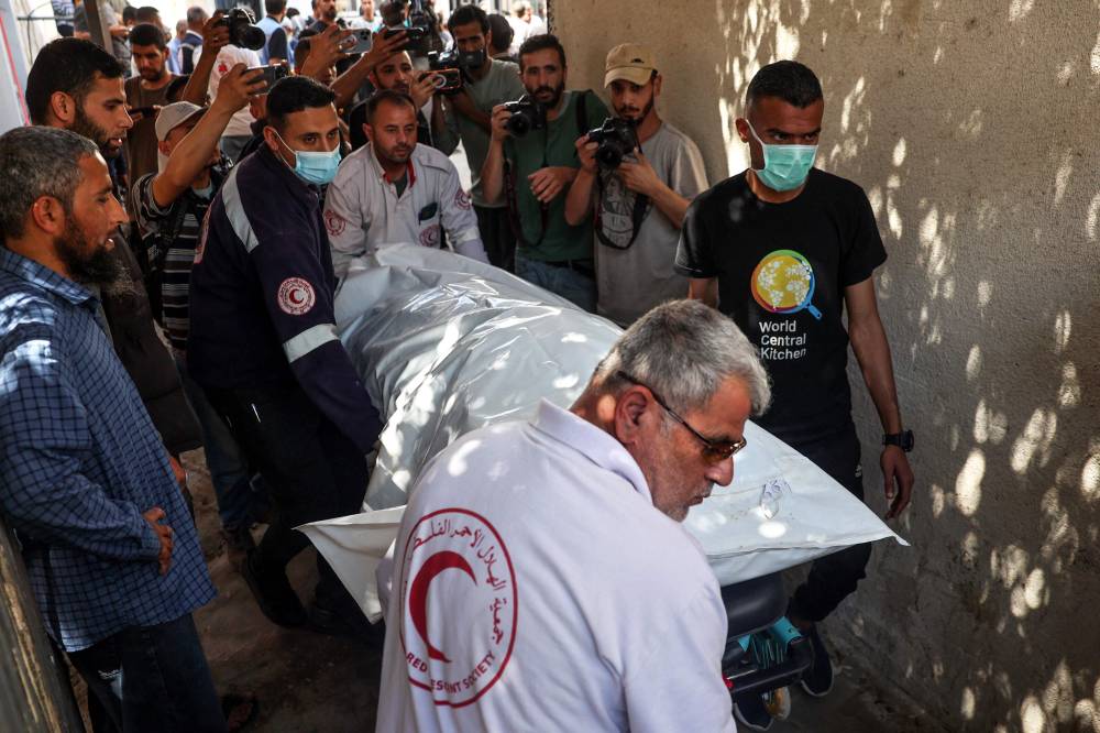 One of the bodies of staff members of the US-based aid group World Central Kitchen, is transported out of a hospital morgue in Rafah. Photo by Said Khatib/AFP