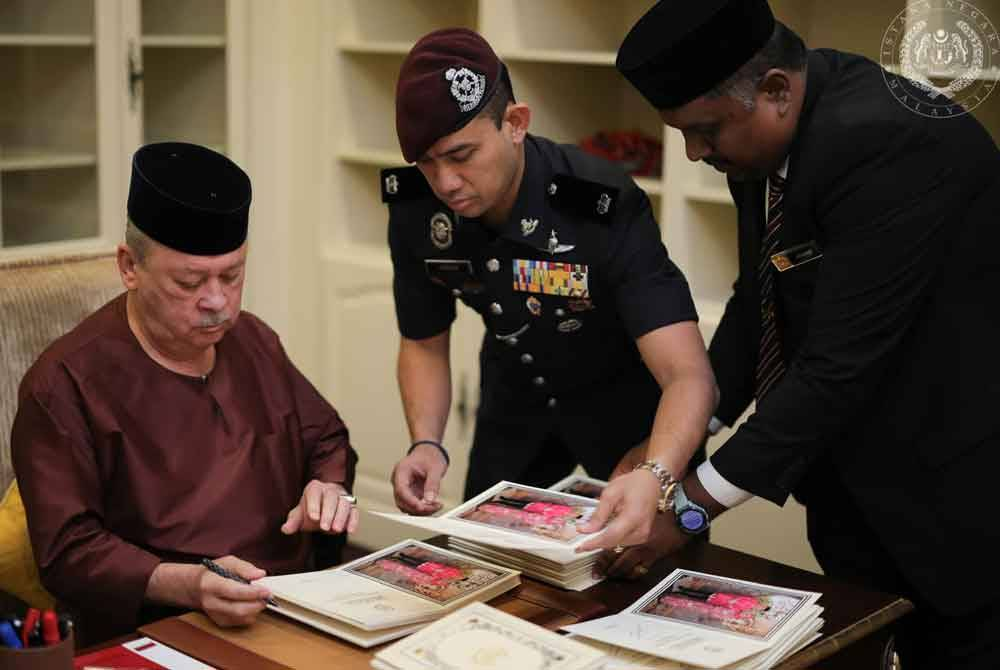 Yang di-Pertuan Agong Sultan Ibrahim signing Raya cards. 