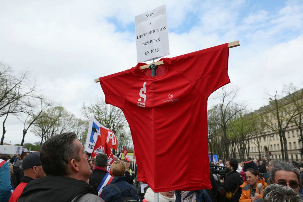 A protestor holds a SEB group t-shirt with a placard reading "no to the ban of PFAS in 2025" as employees, managers and unionists of French cookware and small appliance manufacturer Tefal, owned by Groupe SEB, take part in a protest against a proposed law aimed at banning Per- and polyfluoroalkyl substances (PFAS) in France from 2026, which will affect almost 600 employees, at Place des Invalides in Paris on April 3, 2024. - Photo by AFP