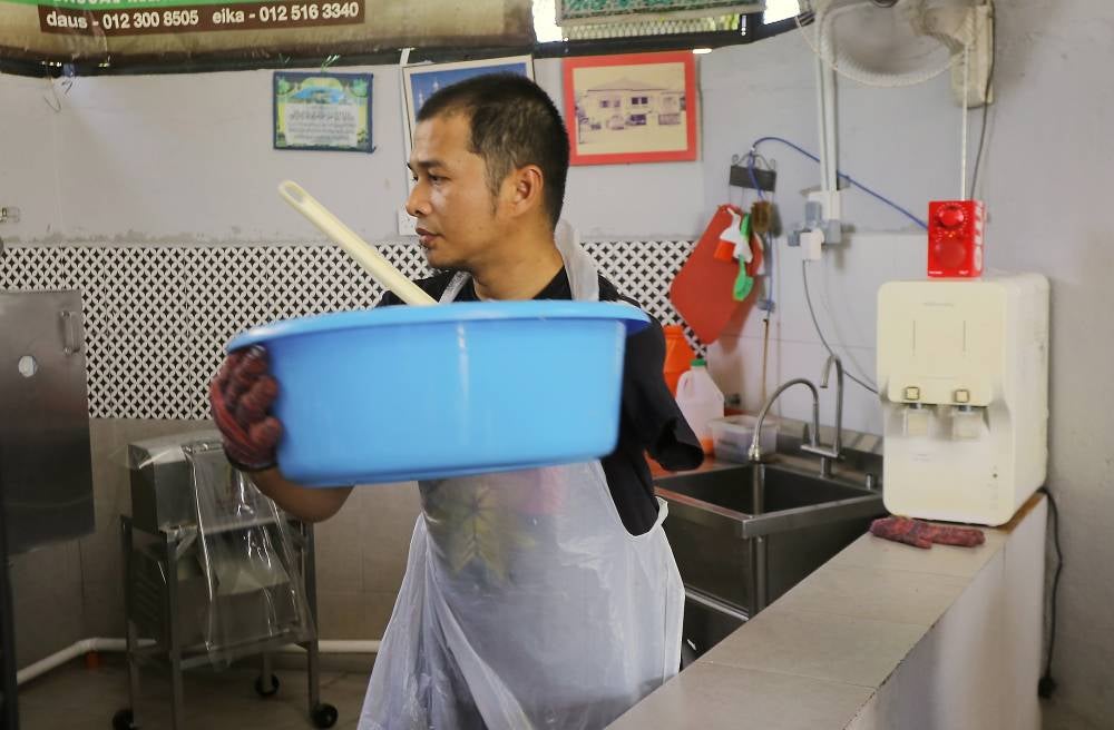 Owner of Santan M'darat Mohd Firdaus Ismail, 40, carrying out the process of squeezing coconut milk when met in Kampung Sungai Rokam, Ipoh. - Photo by Bernama