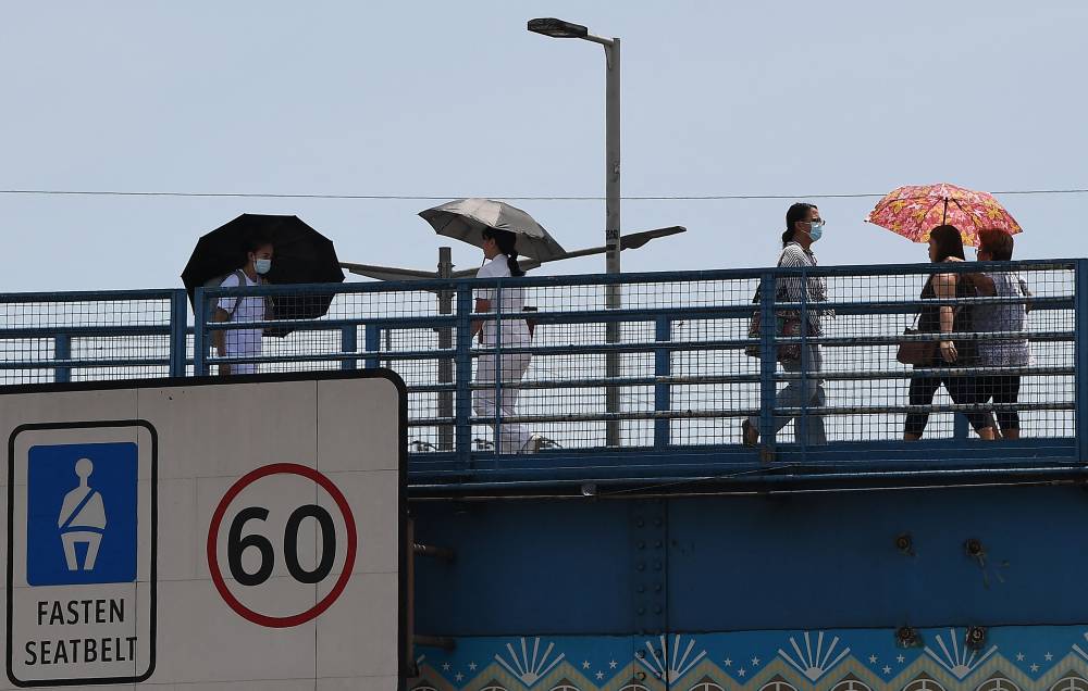 Pedestrians hold umbrellas to protect them from the sun cross a footbridge in Manila on April 8, 2024. - Photo by AFP