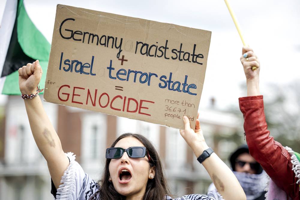 A woman holds a placard as people protest outside the ICJ, as lawyers gather for a case filed by Nicaragua against Germany demanding judges impose emergency measures to stop Berlin providing Israel with weapons and other assistance, in the Hague on April 8, 2024. - (Photo by Robin van Lonkhuijsen / AFP)