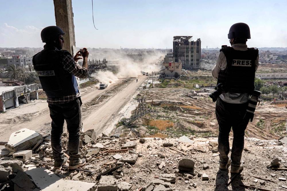 Journalists film from atop a damaged building facing the ravaged building of al-Salam hospital in Khan Yunis after Israel pulled its ground forces out of the southern Gaza Strip. Photo by AFP