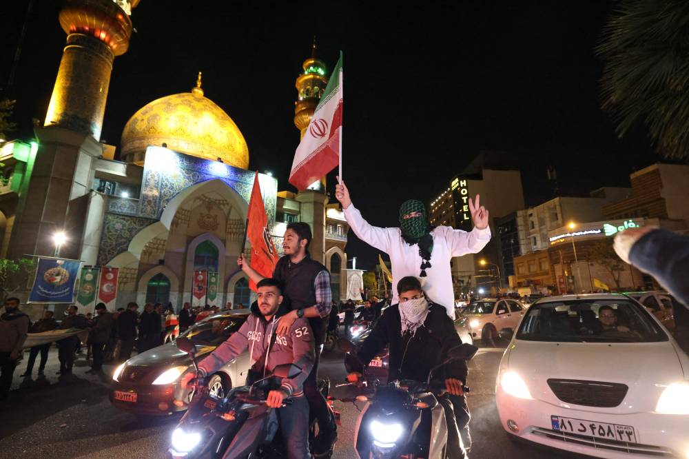 Demonstrators wave Iran's flag and Palestinian flags as they gather at Palestine Square in Tehran on April 14, 2024, after Iran launched a drone and missile attack on Israel. - Photo by AFP