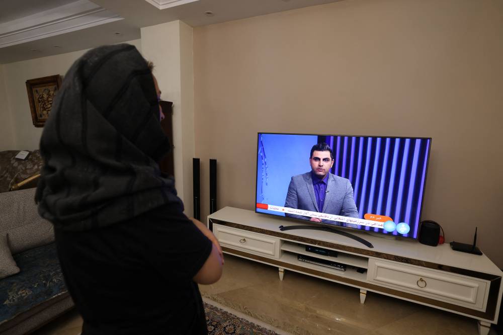 An Iranian woman watches an Iranian news TV channel, which is covering the news of Iran's attack on Israel, on April 14, 2024. - Photo by AFP