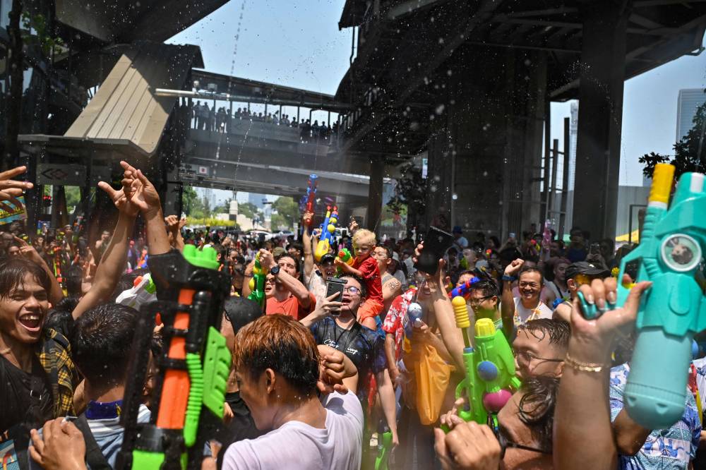Revellers take part in mass water fights on the first day of Songkran, or Thai New Year, on Silom Road in Bangkok. Photo by Lillian Suwanrumpha/AFP